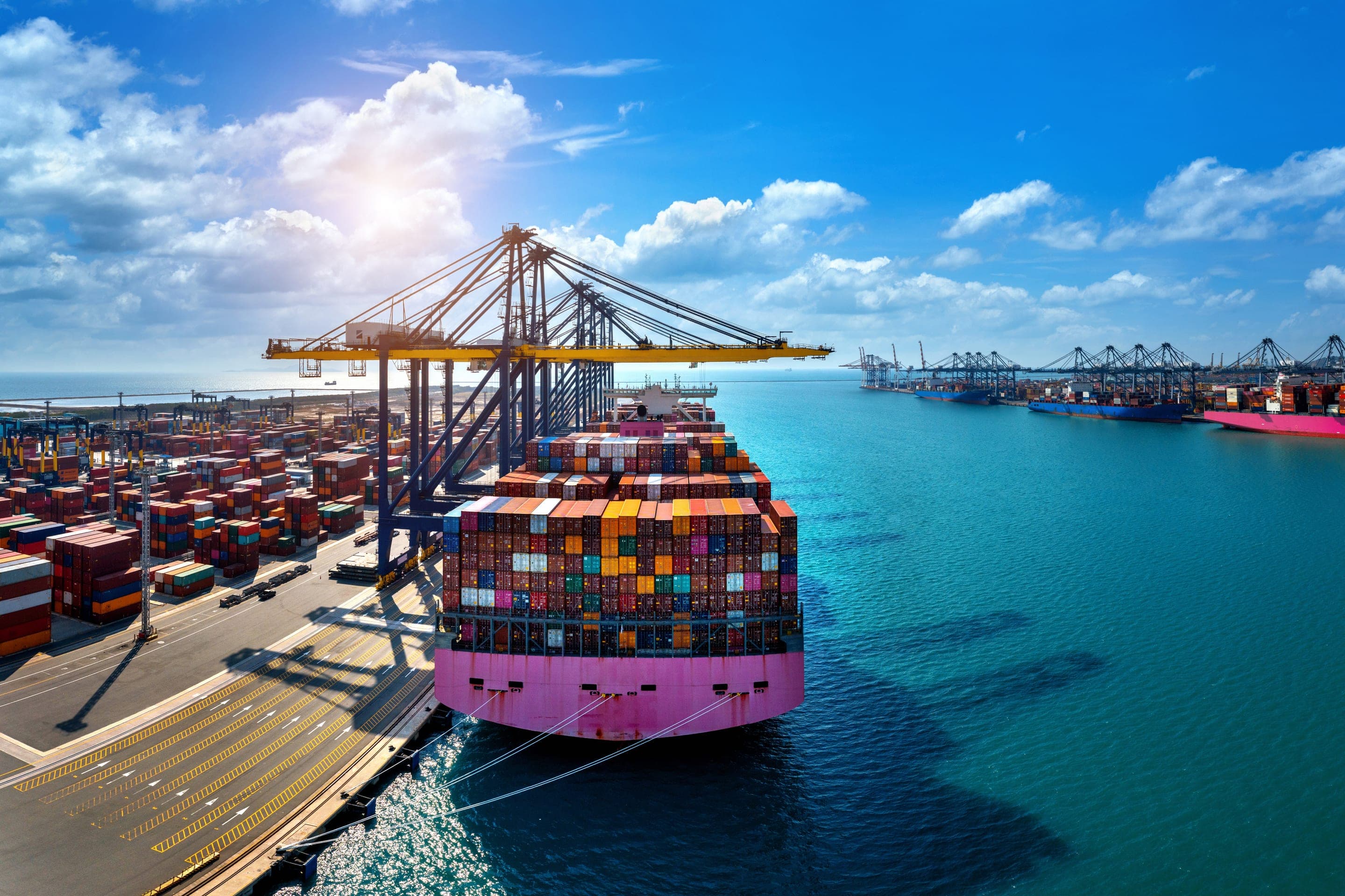 Cảng container với cần cẩu giàn và tàu hàng trên biển